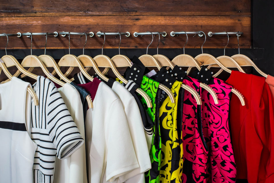 Many blouses on hangers in the dressing room.