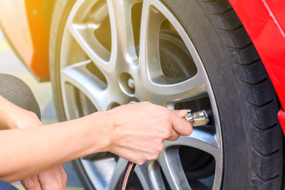 Woman Filling air into a car tire to increase pressure
