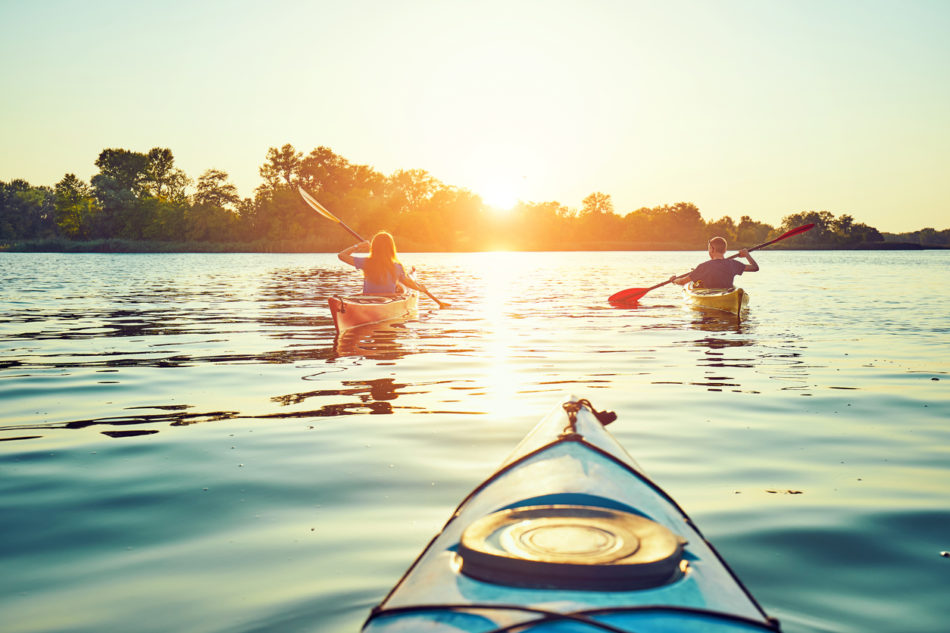 Kayaking couple ride along the river at sunset