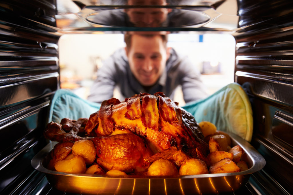 Man Taking Roast Turkey Out Of The Oven. Smiling