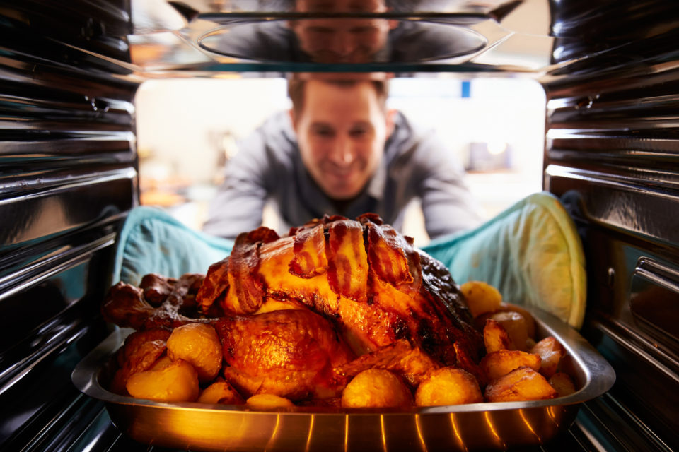 Man Taking Roast Turkey Out Of The Oven. Smiling